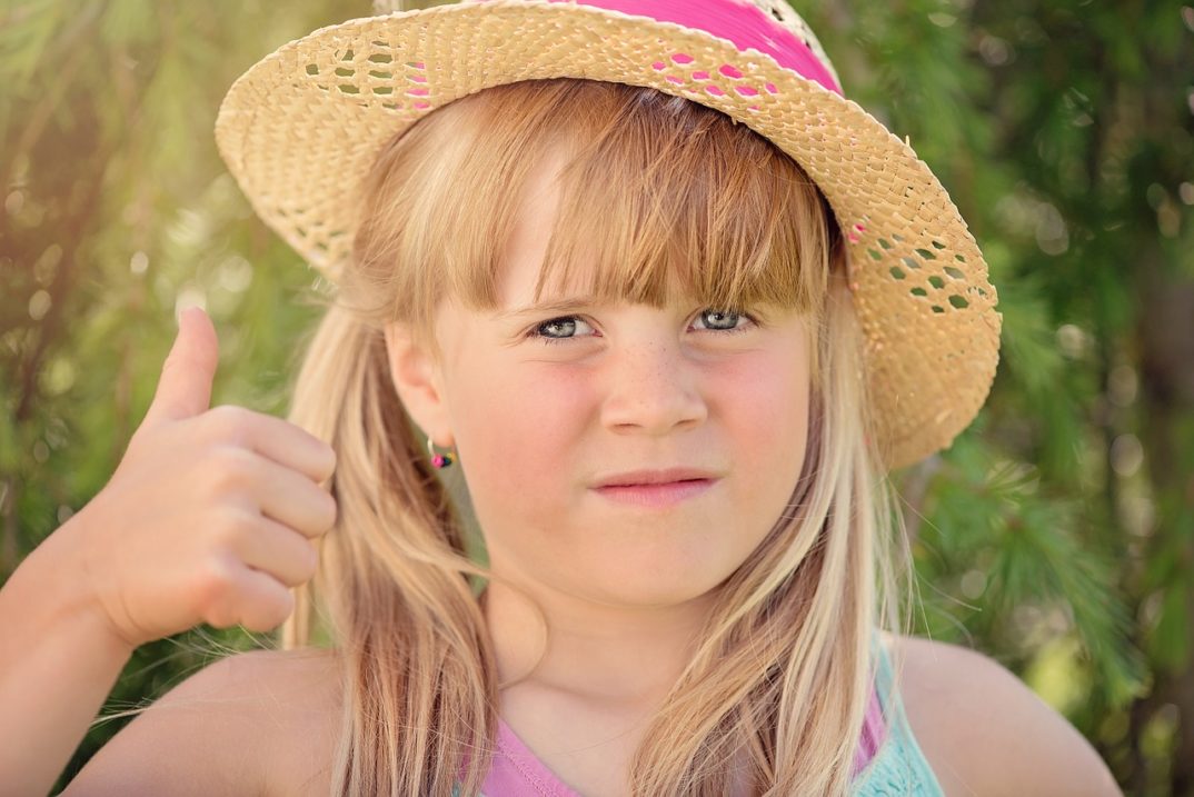 photograph of unsmiling girl giving thumbs up
