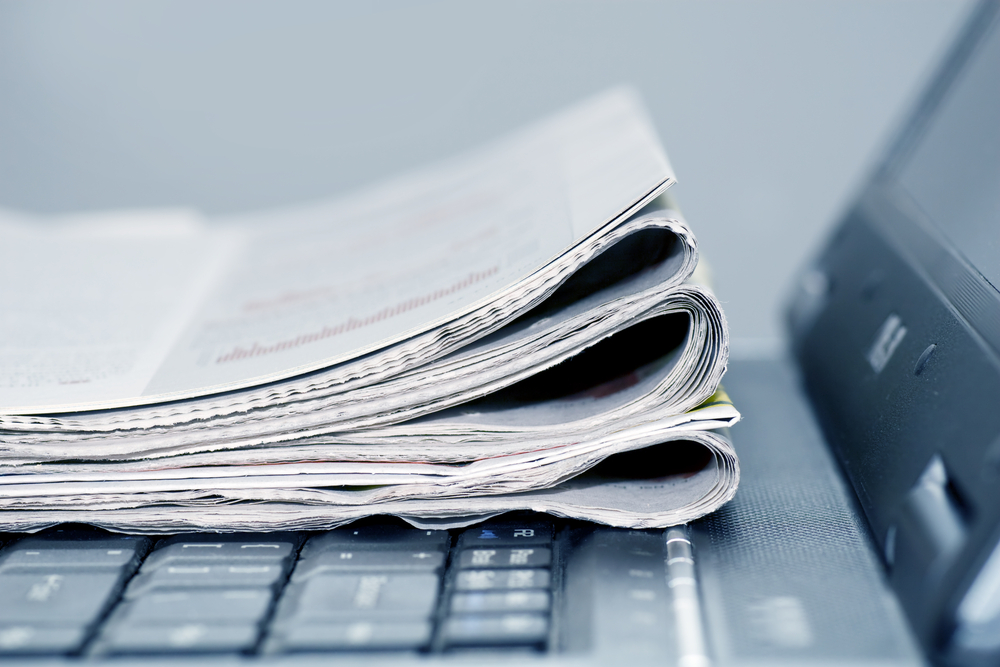 photograph of newspapers folded on top of laptop keyboard