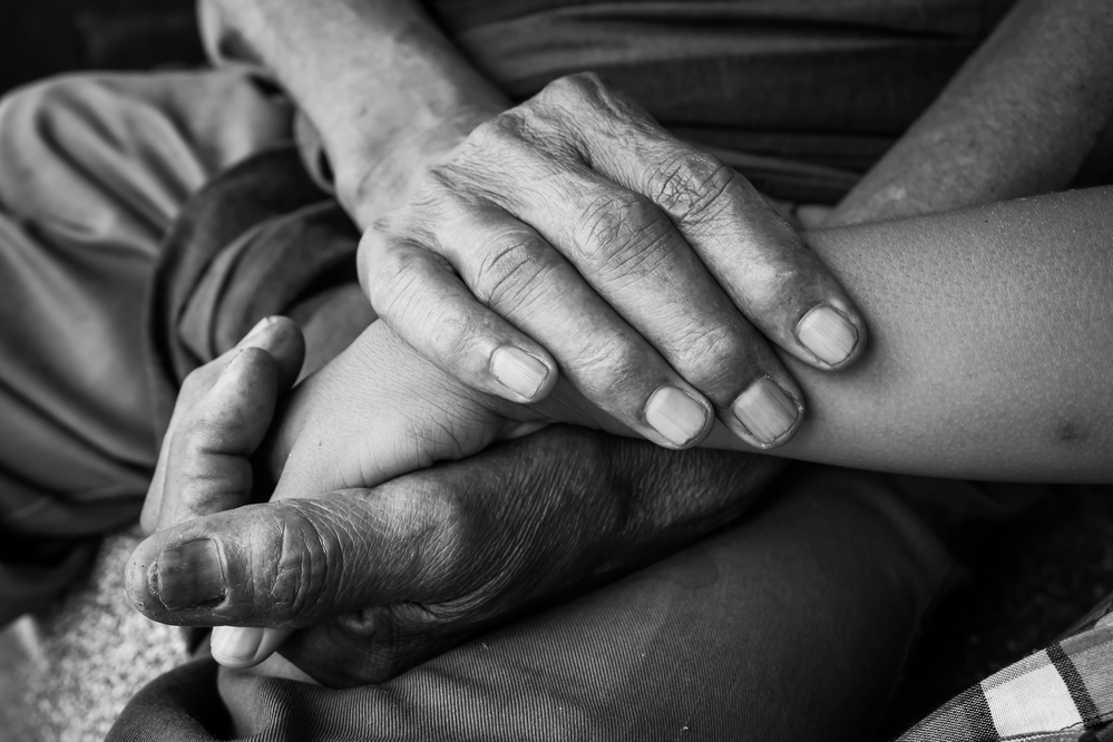 black and white photograph of old and young hands touching