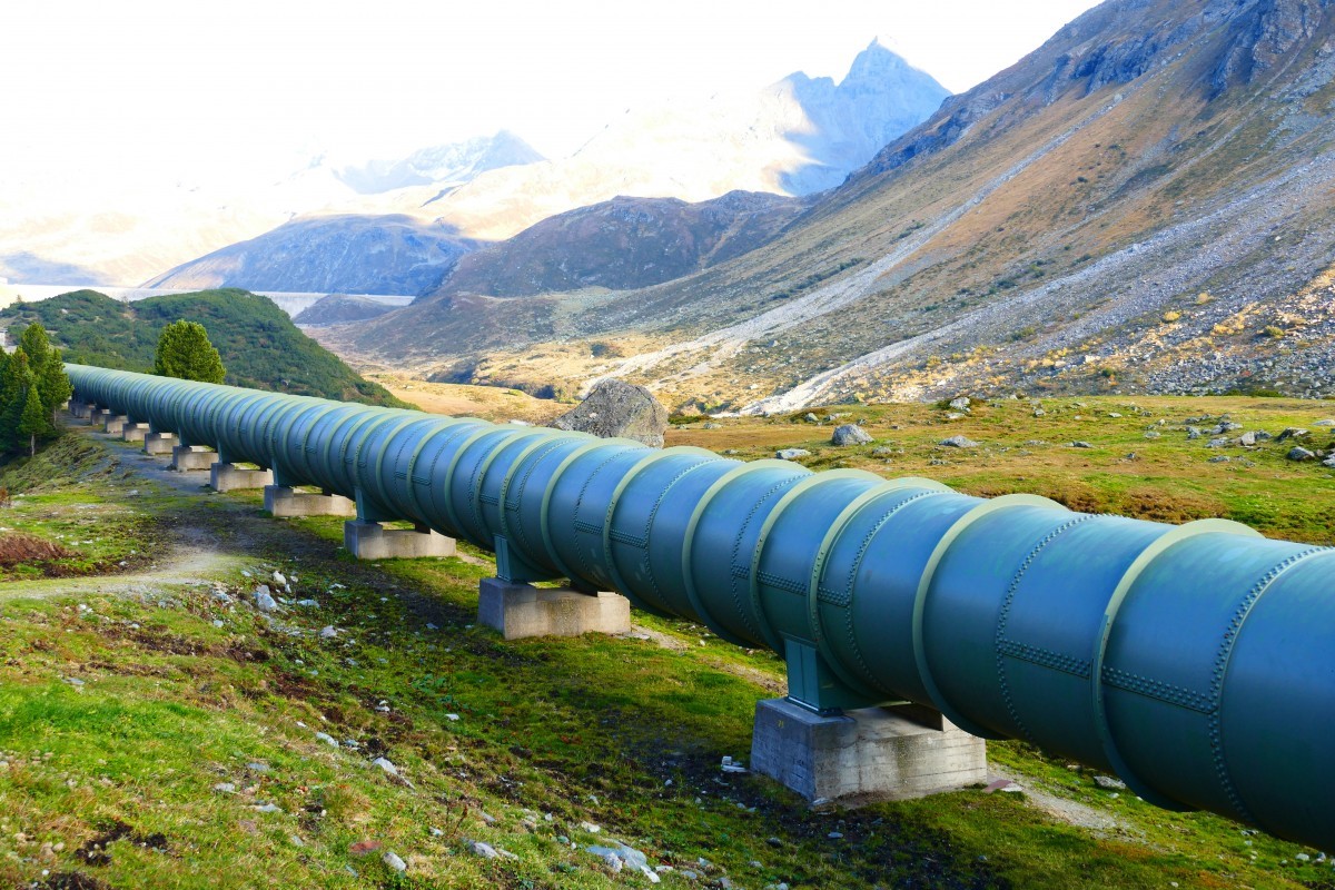 photograph of pipeline through open land with mountains
