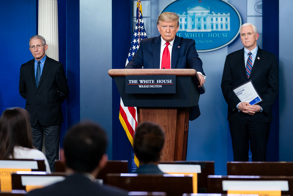 photograph of Trump answering questions at press briefing with Vice President Pence and Dr. Fauci one either side