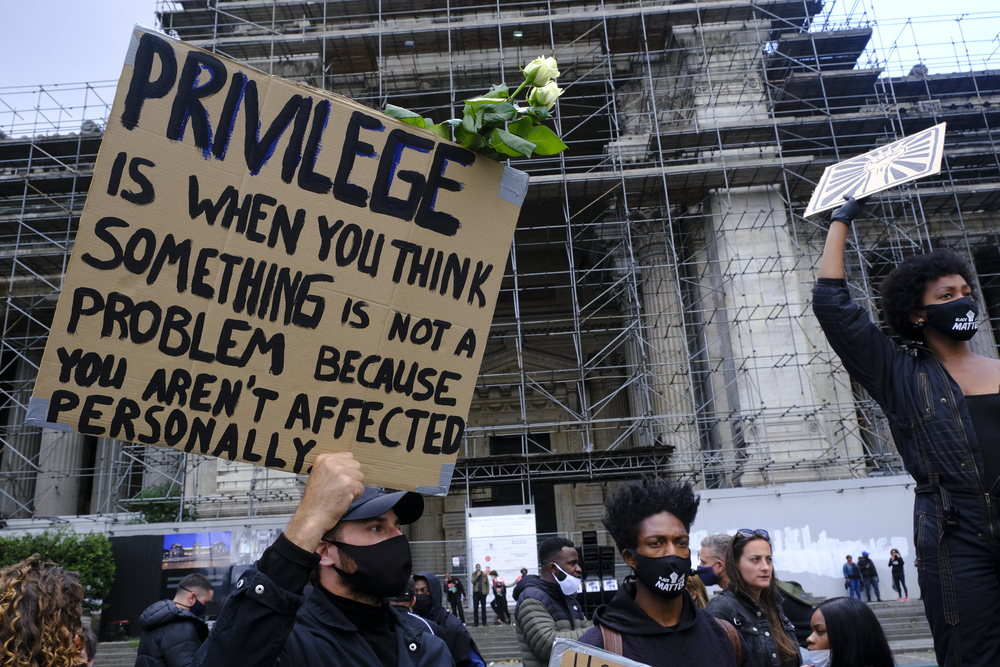 photograph of BLM protester with sign explaining white privilege