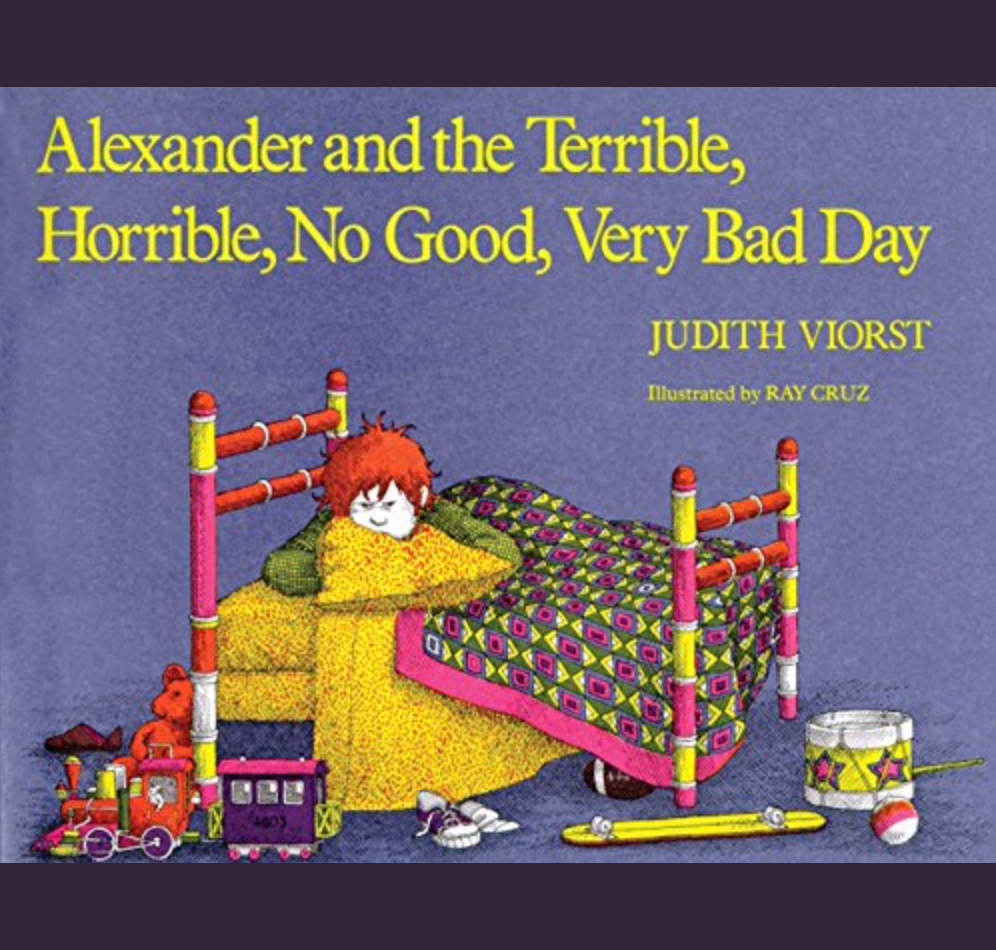 Illustration for the Alexander and the Terrible, Horrible, No Good, Very Bad Day book cover of a young white boy with red hair in the middle of a four-poster bed under a colorful quilt. There is an assortment of toys and clothes littering the floor near his bed. The boy has a sour expression on his face.