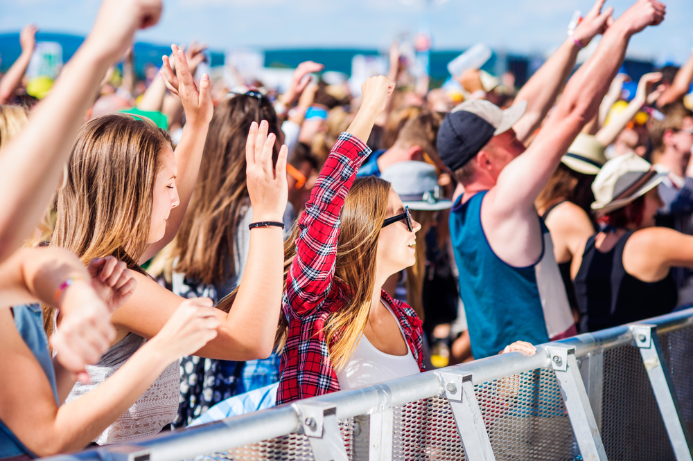 photograph of teenagers at corwded concert on the beach