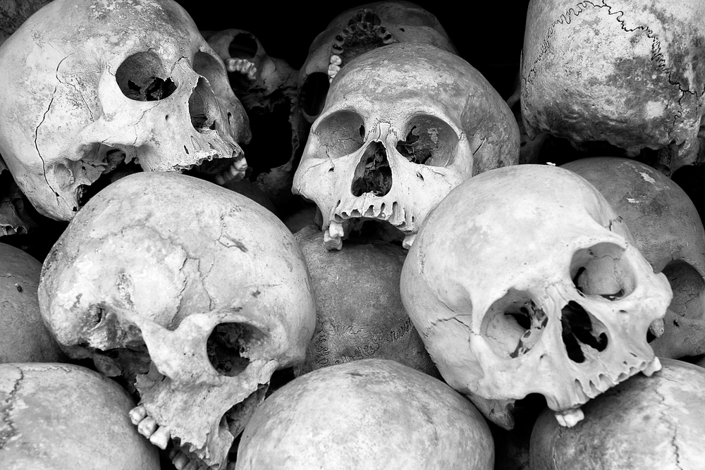black and white photograph of human skulls stacked on top of one another