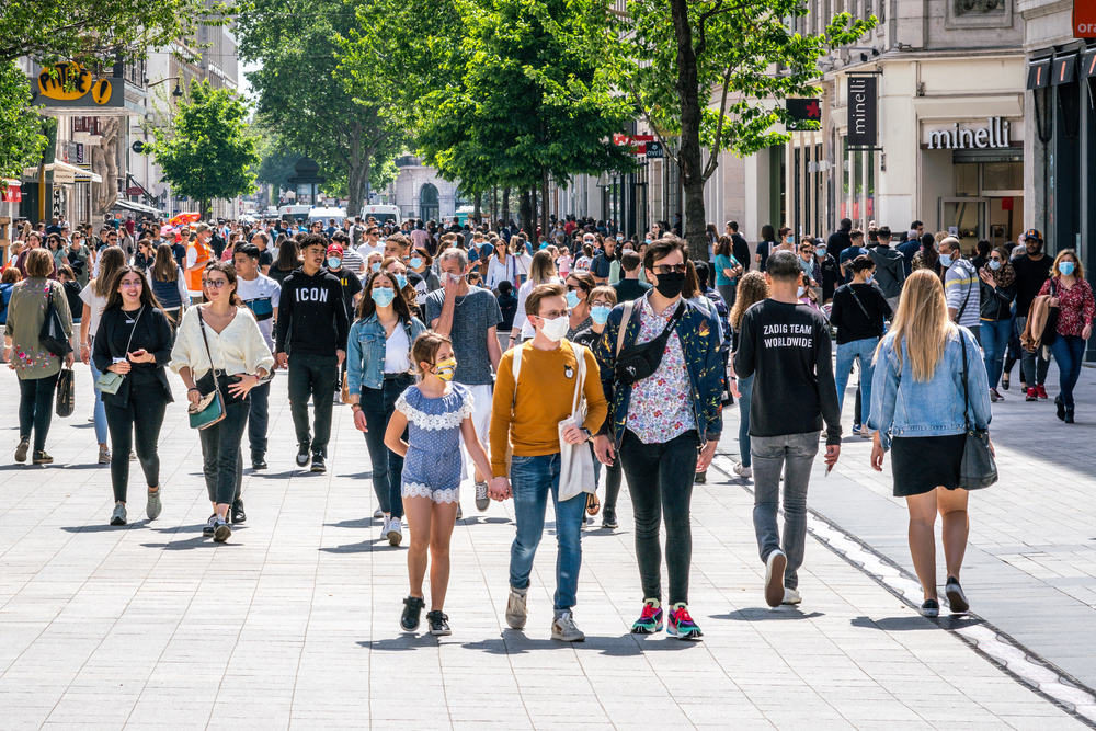 photograph of large crowd walking through strip mall