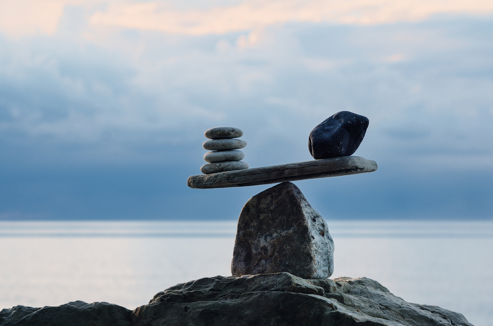 photograph of scales made of pebbles balanced on a boulder