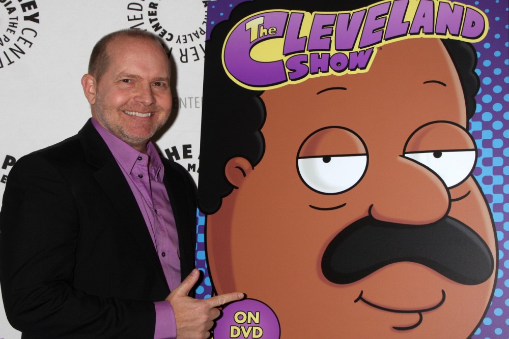 photograph of Mike Henry beside poster of Cleveland character he voices