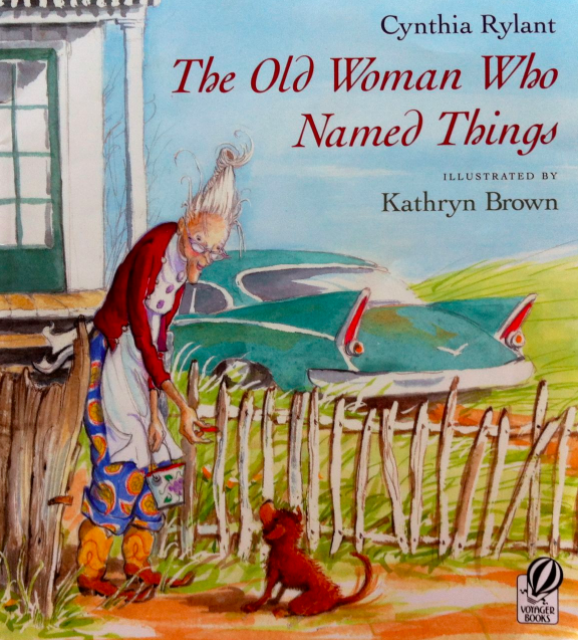 Illustrated book cover for The Old Woman Who Named Things featuring an elderly white woman handing food to a small brown puppy. She has tall white hair, glasses, and colorful clothing. She is standing at a wooden fence in front of her house and car.