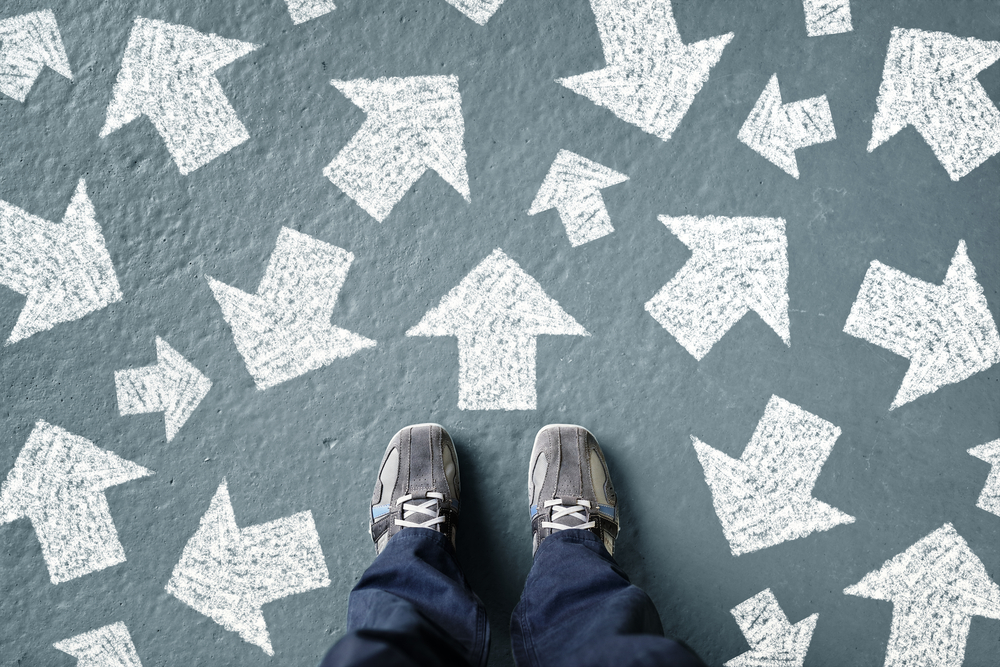 photograph of feet standing before numerous direction arrows painted on ground