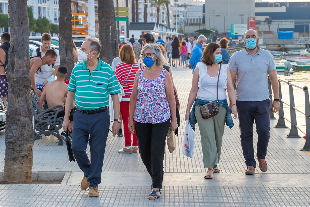 photograph of groups of people walking on busy street wearing protective masks