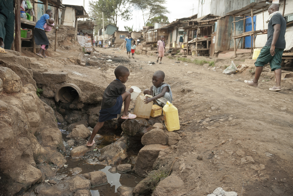 photograph of boys filling water jugs from a ditch in Kenya