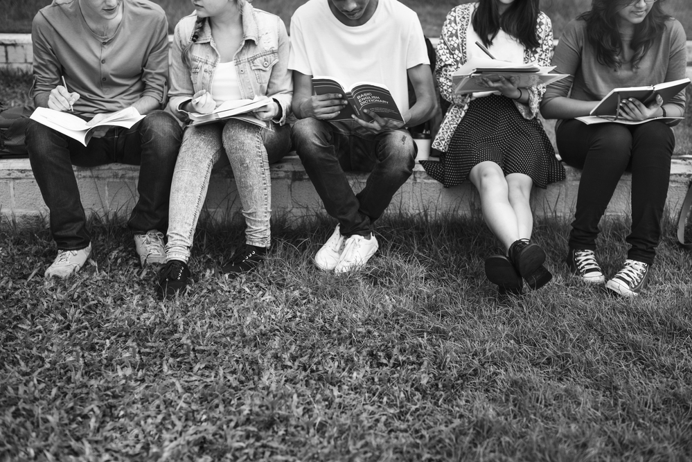 black-and-white photograph of group of students studying outside