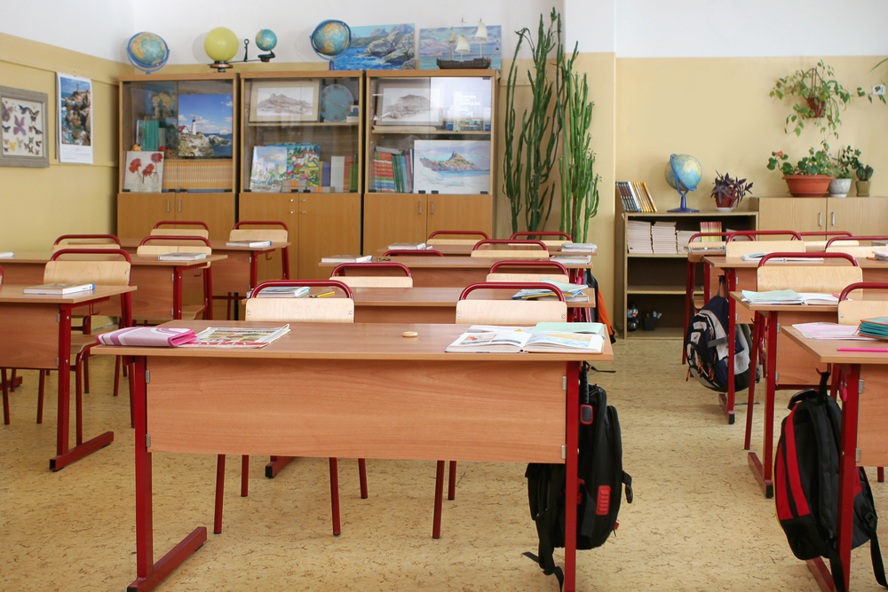 photograph of empty elementary school classroom filled with books and bags