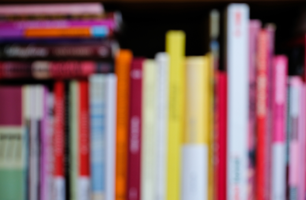 blurred photograph of bookshelf with birght, colorful books