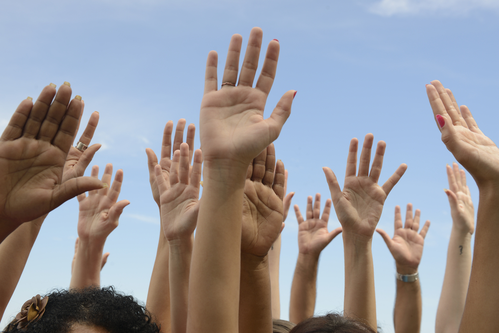 photograph of group of hands raised