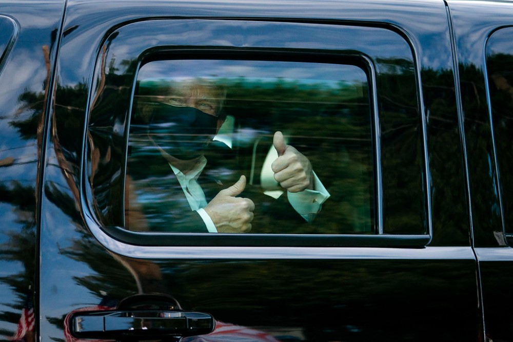 photograph of President Trump with face mask giving thimbs up from within SUV