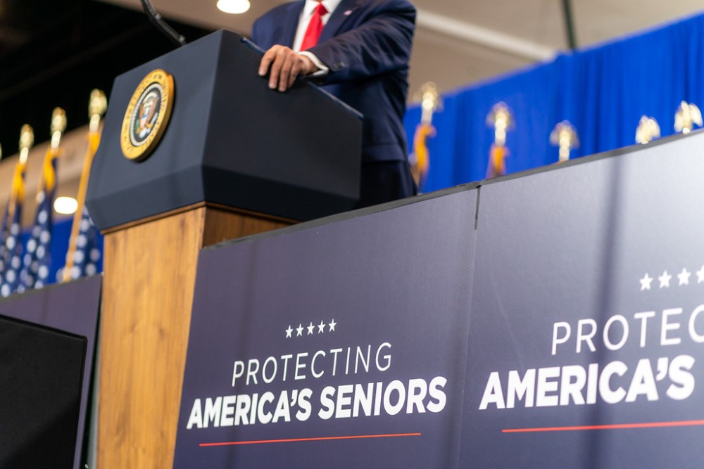 photograph of "protecting america's seniors" sign next to podium with presidential seal