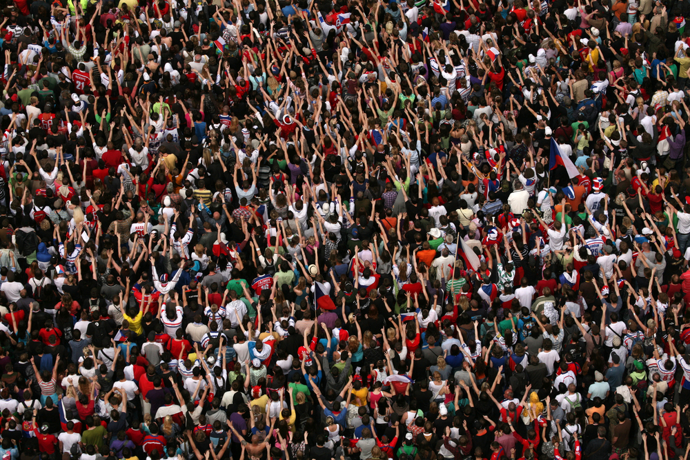 photograph of huge crowd from above, many with arms raised