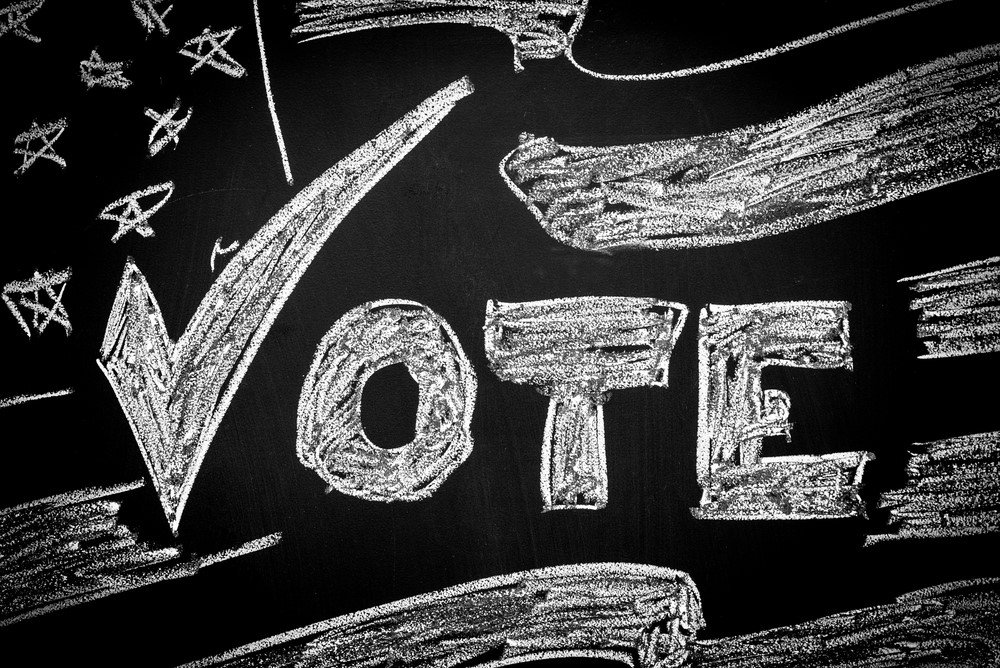 photograph of "Vote" written on chalkboard with drawing of American flag
