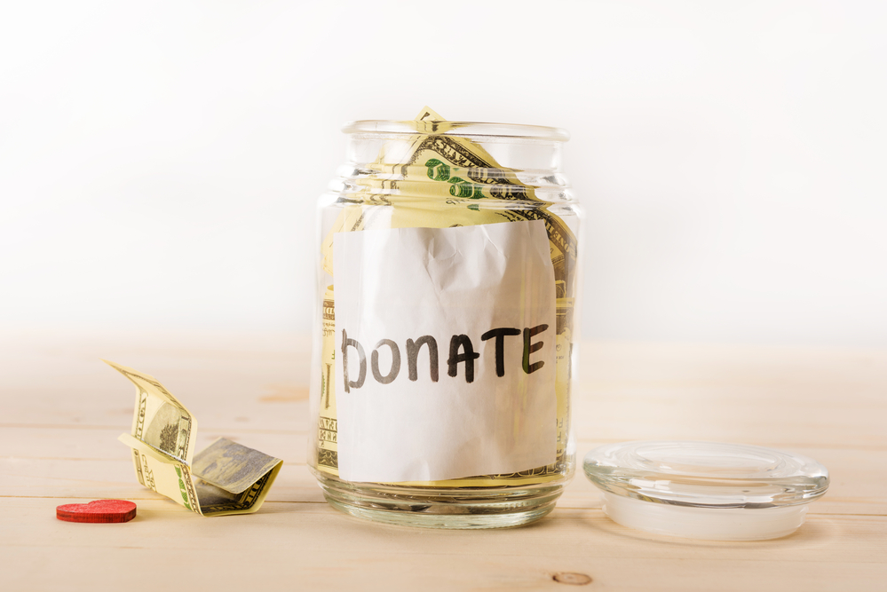 photograph of donation jar stuffed with large bills