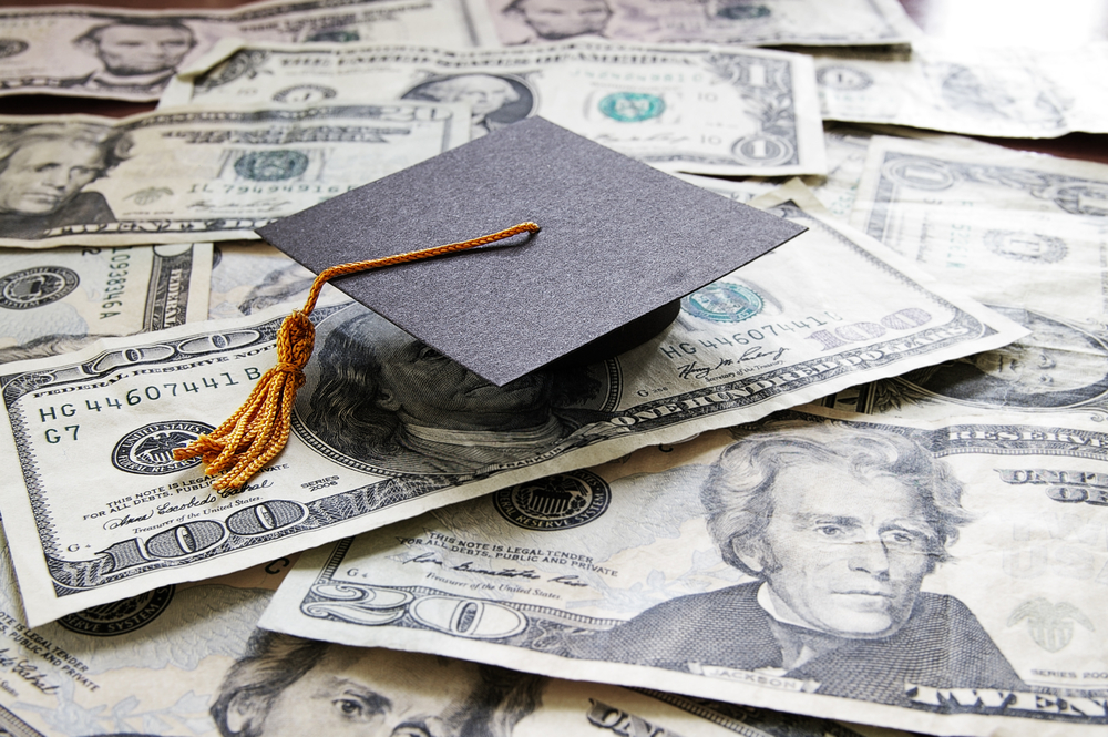 photograph of college graduation cap laying on top of pile of cash