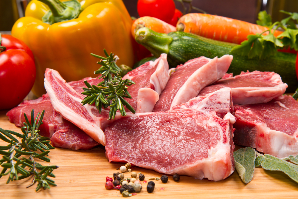 photograph of raw lamb cutlet surrounded by vegetables