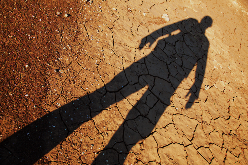 photograph of human shadow stretching out over dry lakebed