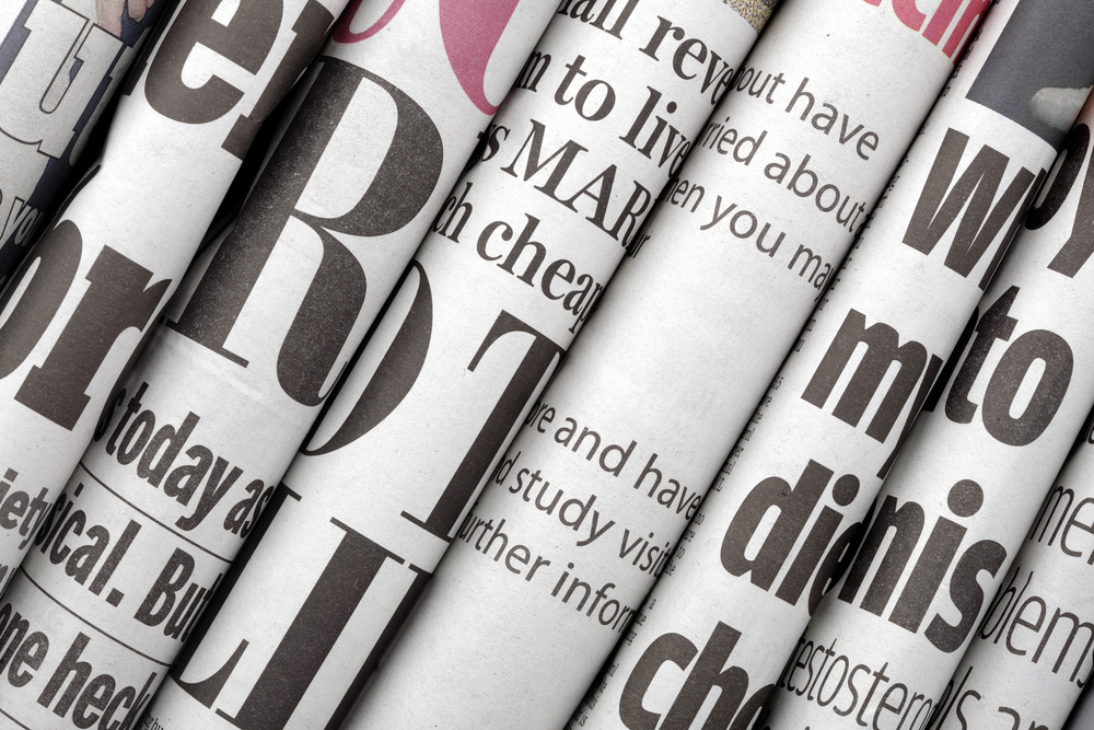 photograph of partial newspaper headlines arranged in a stack