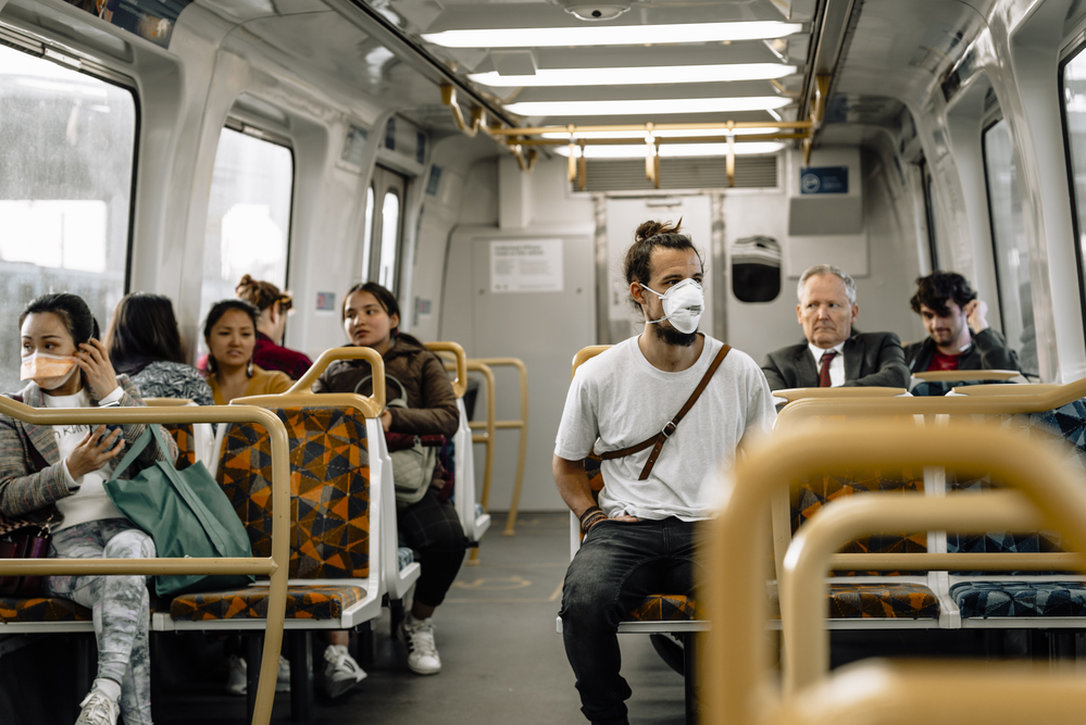 photograph of full subway car with half of the passengers unmasked