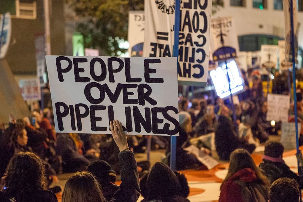photograph of protestors with "People over Pipelines" sign