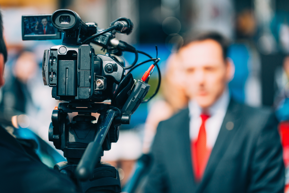 photograph of news camera recording press conference