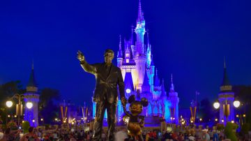 photograph of Walt Disney Statue with Disney Castle in background