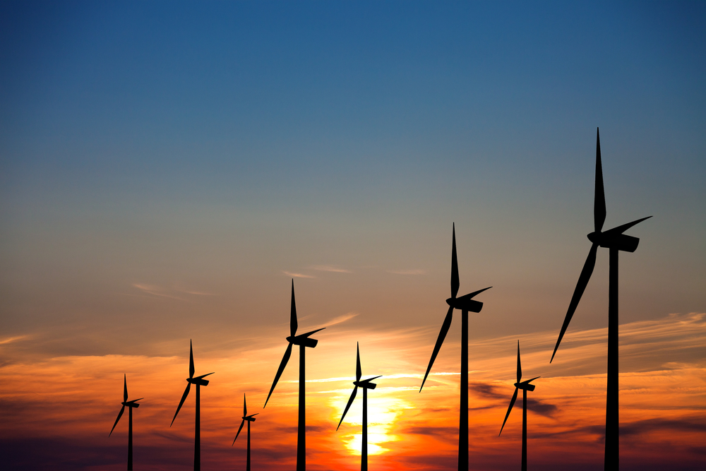 photograph of wind turbines at sunset