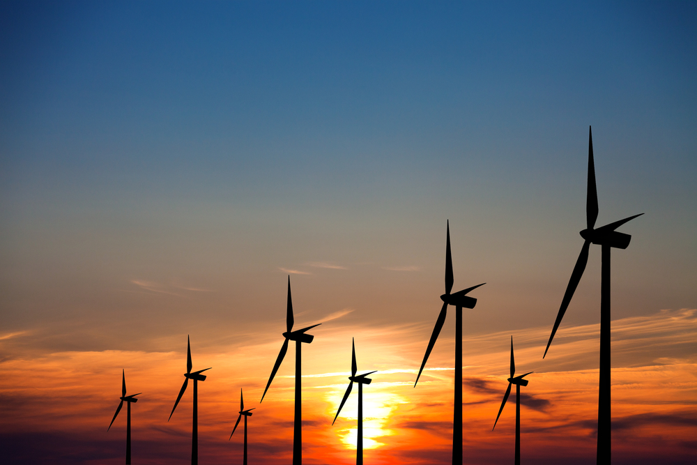 photograph of wind turbines at sunset