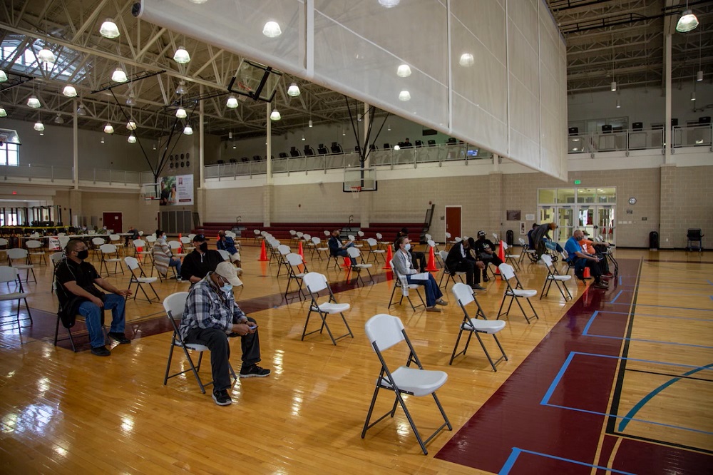 photograph of patients waiting in gym to be vaccinated