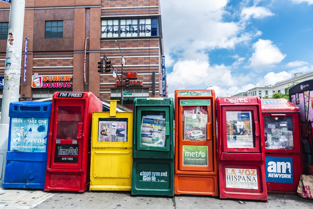 photograph of newspaper vending machines with businesses in background