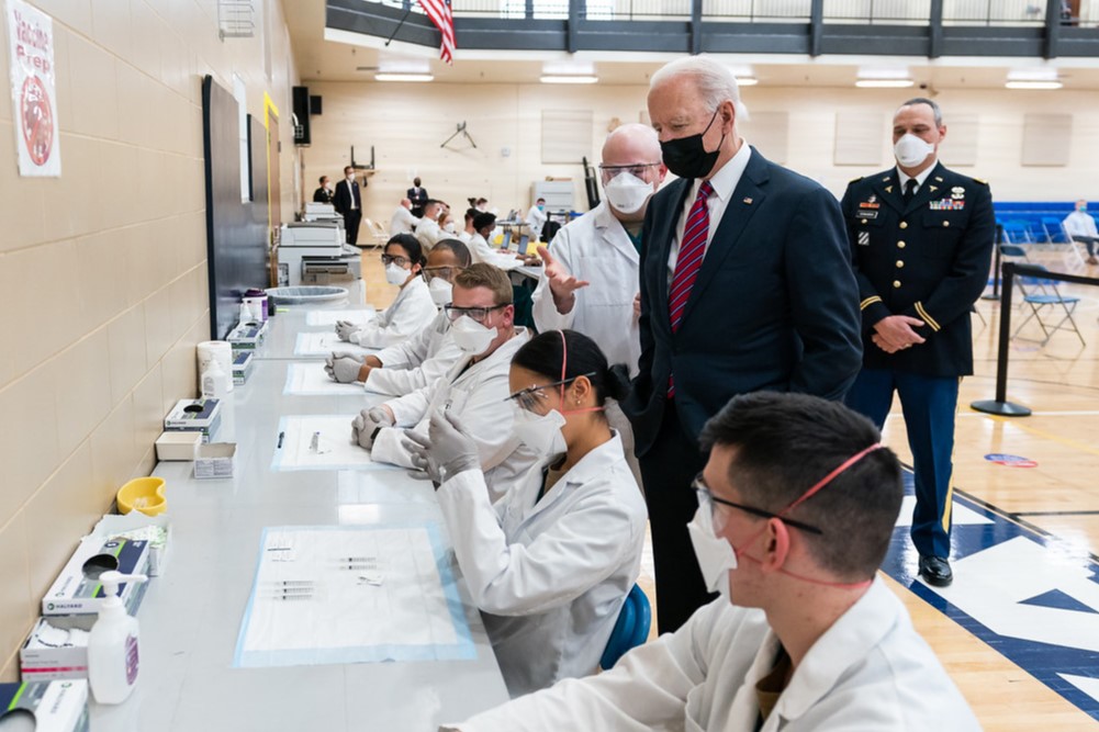 President Joe Biden observes dosage preparations during a tour of a vaccination center