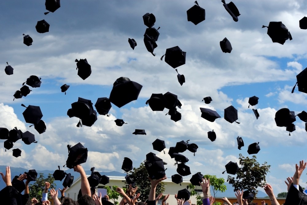 photograph of graduation caps thrown in the air