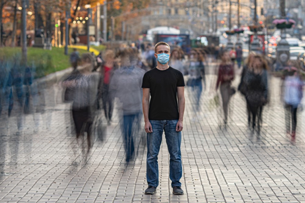 photograph of masked man amongst blurred crowd