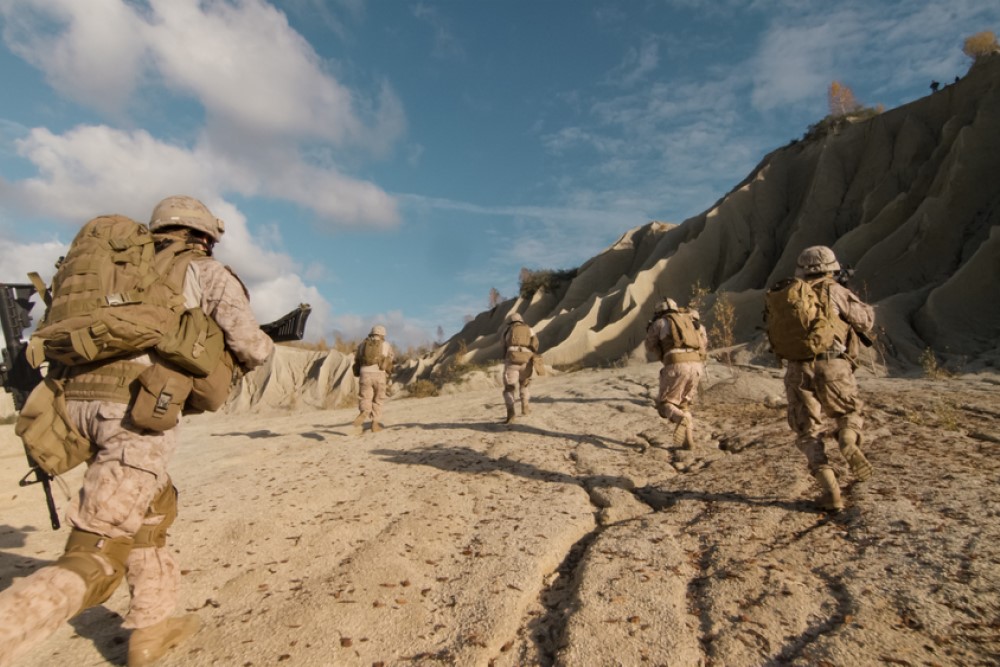 photograph of soldiers running in the desert