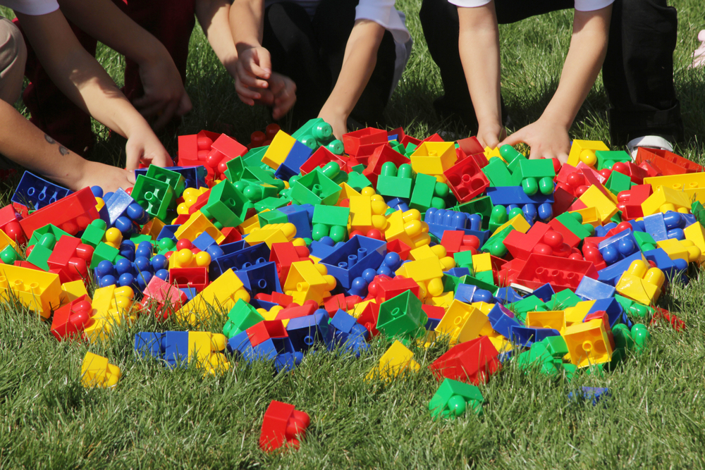 photograph of children playing with LEGOs in the grass