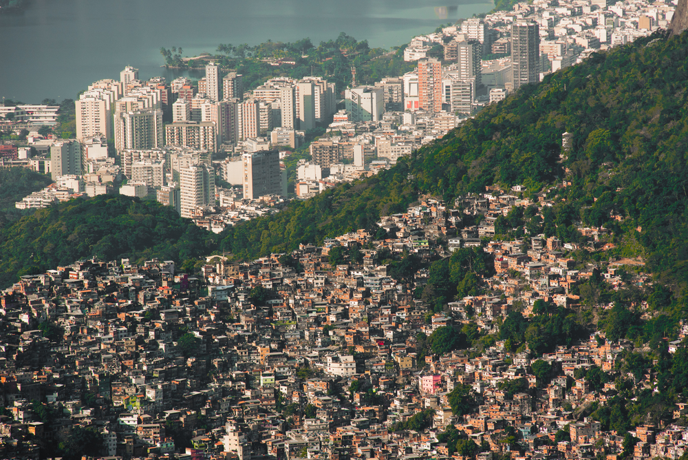 photograph of favella next to skyscrapers