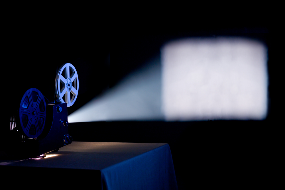 photograph of old movie projector displaying blank image on screen