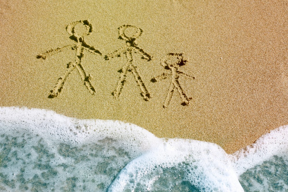 photograph of stick family carved into beach