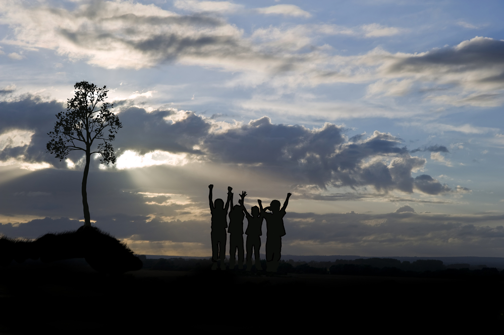photograph of four silhouetted youths at sunset