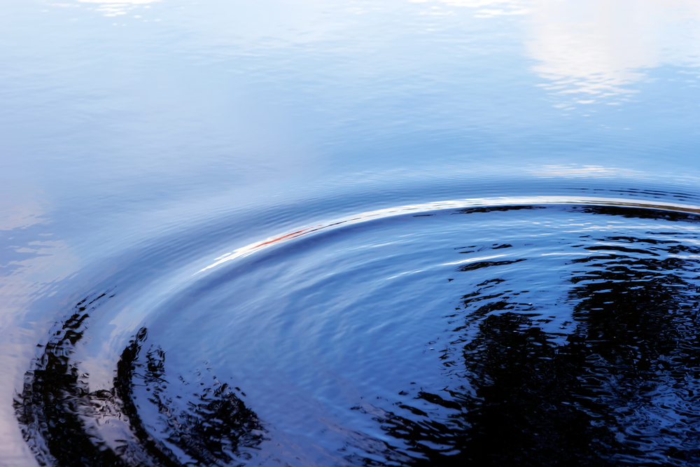 photograph of ripple on lake expanding