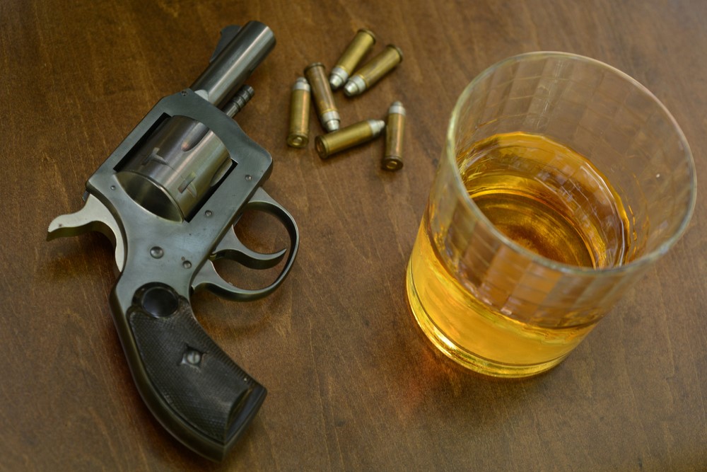 photograph of gun with bullets and glass of alcohol on table