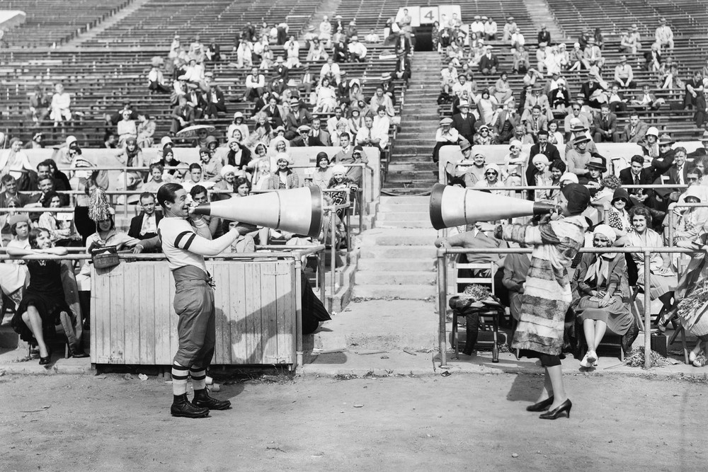 black-and-white photograph of man and woman yelling into megaphones