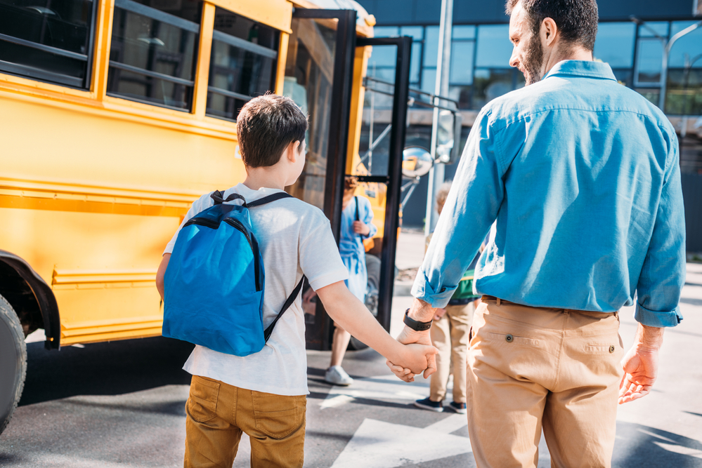 photograph of parent walking son to schoolbus